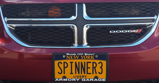 Close-up on a license plate on a red Dodge van reading: SPINNER3