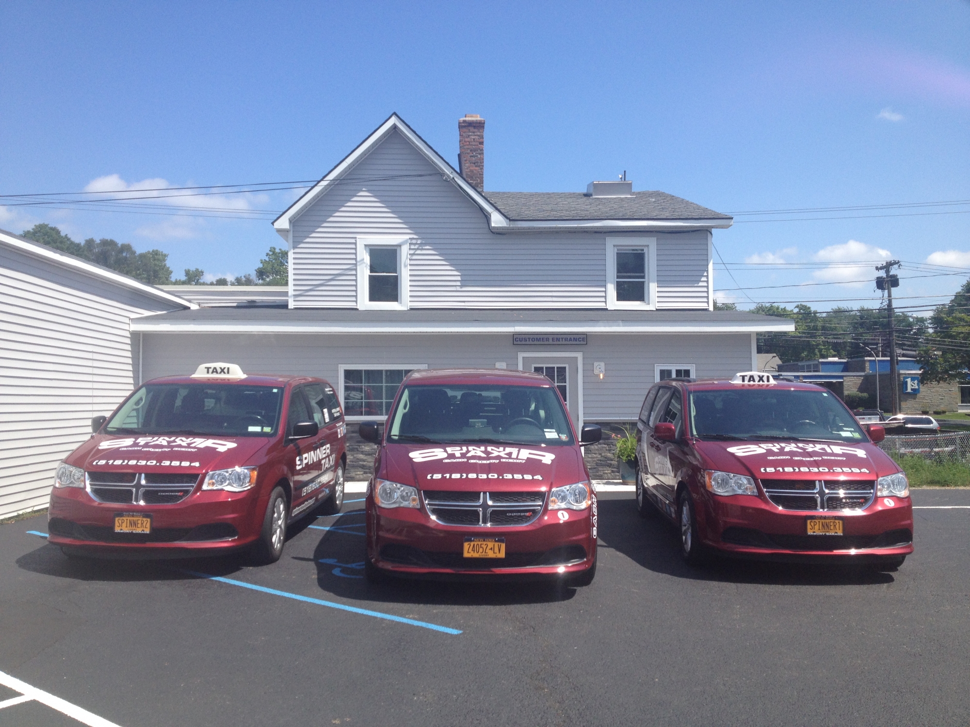 Three Spinner Taxi vehicles parked outside on a clear, sunny day