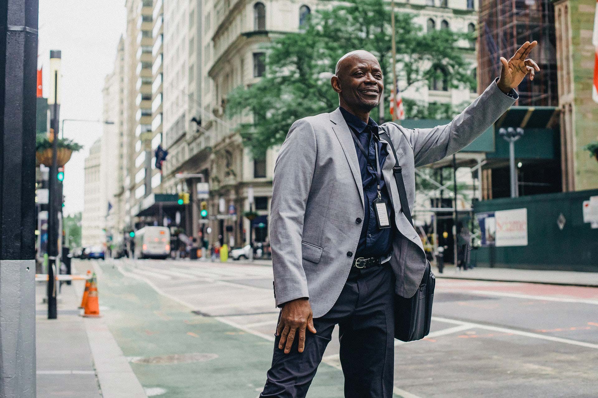 A man in a grey jacket hailing a cab