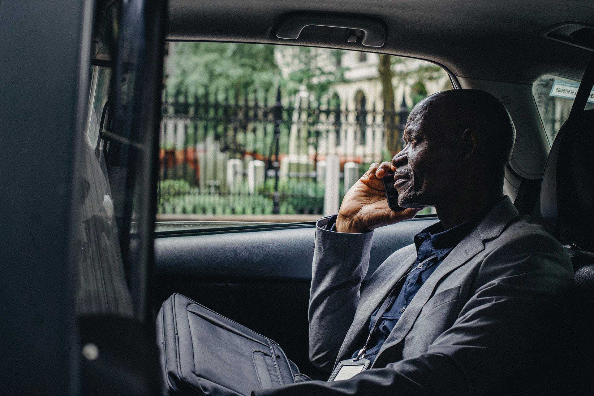 A man on his phone in the back seat of a taxi